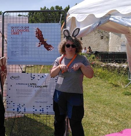 Photo de Bookynette qui porte des oreilles de lapin, devant deux panneaux de l'Expolibre de l'April