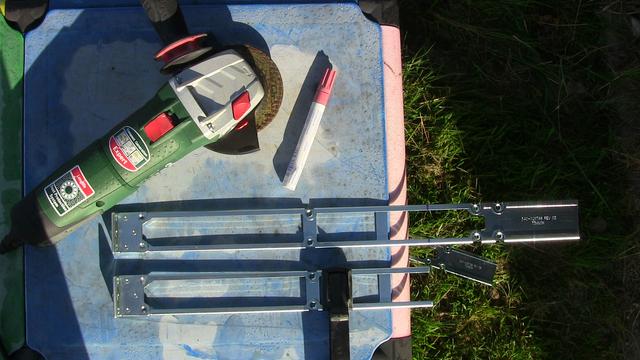 Rack-Montageschienen auf buntem Plastiktisch im Garten fixiert - eine mit Flex gekürzt