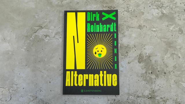 Das Buch liegt auf einer grauen Betonfläche. Das Buchcover ist schwarz gehalten und mit grellen grünen und gelben Buchstaben gestaltet. Links dominiert ein großes gelbes „N“, das etwa drei Viertel der Seite einnimmt. Oben rechts steht zweizeilig in grünen Buchstaben der Name des Autors. Direkt darunter befindet sich die Grafik einer Sonne – sie schwitzt und streckt eine grüne Zunge heraus. Zusammen mit dem Buchstaben „N“ ergibt sich so das Wort „No“ als erster Teil des Titels. Ganz rechts daneben ist untereinander das Wort „Roman“ in grüner Schrift gesetzt. Darauf folgt – über die gesamte Breite des Covers – der zweite Teil des Titels: „Alternative“, in kräftigem Gelb. Mittig darunter steht in kleinen grünen Versalien der Name des Verlags.