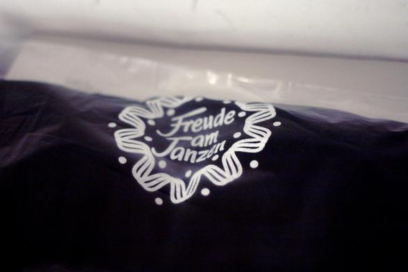 Originalverpacktes T-Shirt vom "Freude am Tanzen" Label. Weiße Schrift auf dunkelblauem Textil.