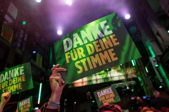 Menschen halten grüne Plakate mit Text "Danke für deine Stimme" in die Höhe.