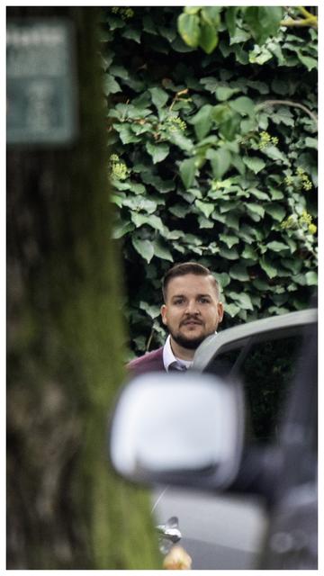 Neonazi Gianluca Bruno am Tag der Urteilsverkündung am 15.09.2022. Sein Kopf zwischen einem Baum und einem Auto fotografiert. 

Um das Bild ist ein kleiner weißer Rahmen