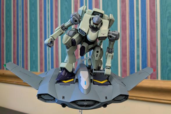 The HG Zowort riding the HG Tickbalang (personal transport vehicle) on a stand. The Zowort is down on one knee holding a raised stability bar.