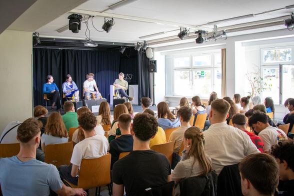 Schüler*innen und Wissenschaftler*innen auf Bühne im Gespräch