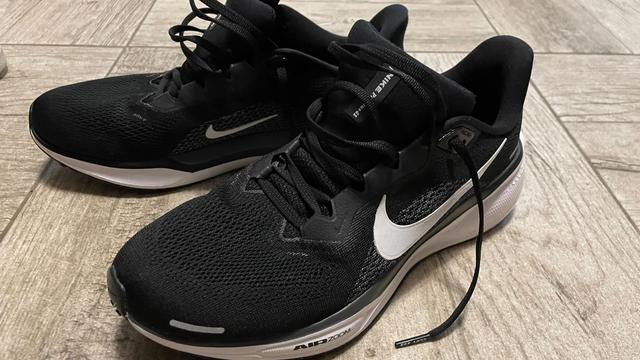 Niken mustat Pegasus 41 juoksulenkkarit vaakealla kivilaattalattialla.