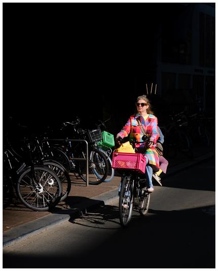 A person cycling and wearing a colorful jacket