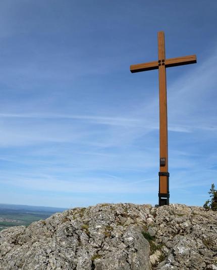 Holzkreuz auf einem Felsen vor blauem Himmel.

Wooden cross on a rocky summit in front of blue skies.