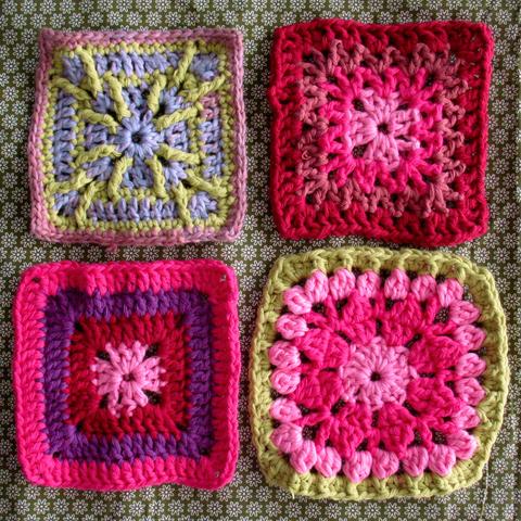 4 different granny squares on a green flower pattern fabric. The granny squares have mostly pink, red, and light green colours.