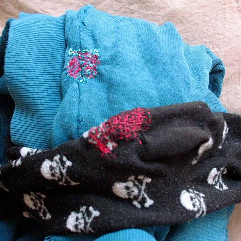 My messy mending skills with red thread on a black skull & bones sock and blue hoodie.