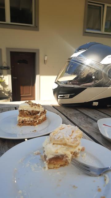 Zwei Teller mit Kuchenstücken und dahinter ein Motorradhelm auf einem Holztisch