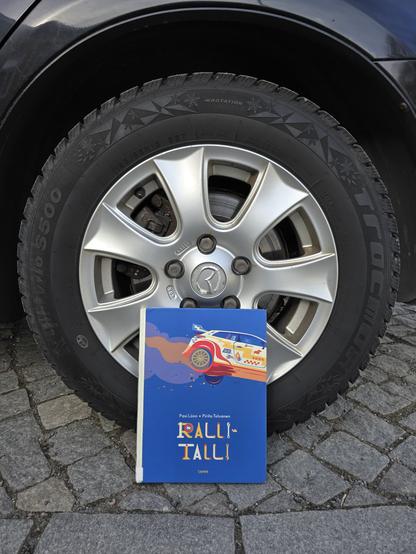 Kuvassa Rallitalli-kirja kuvattuna auton renkaan edessä.