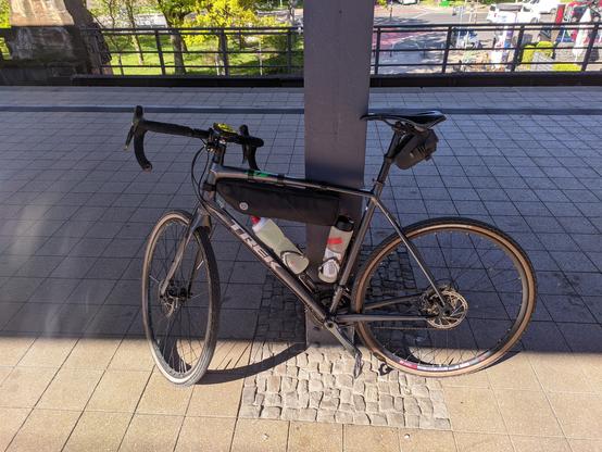 Mein treues Trek Crossrip lehnt an einem Pfeiler am Bahnhof. Es ist mit einer Rahmentasche, Satteltasche und zwei Trinkflaschen beladen.