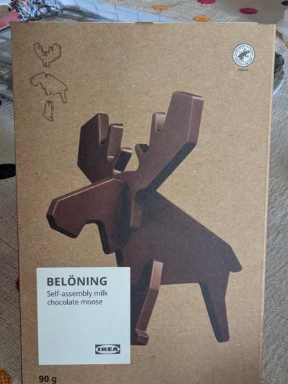 A chocolate Moose with instructions on assembling three planar pieces to make it, in a cardboard wrapper, labelled Belöning.