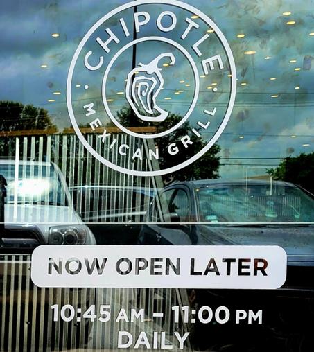 A coear glass door to restaurant chain Chipotle with white lettering:

CHIPOTLE 
MEXICAN GRILL 

NOW OPEN LATER

10:45 AM - 11:00 PM
DAILY