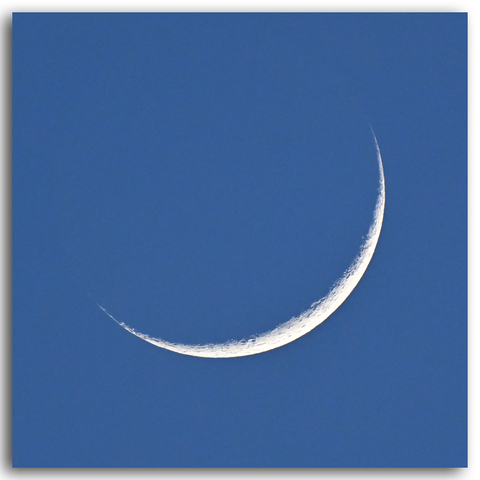 Die schmale Mondsichel kurz nach Neumond (6,2 %) vor blauem Himmel.