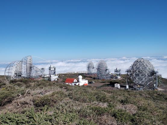 Paisagem: distante, no centro, uma casinha com uma torre de telescópio, que parecem minúsculas comparadas com 5 telescópios gigantes que as circudam. No fundo, um penhasco que dá a ilusão que a montanha termina em um tapete de núvens (na realidade estão bem mais abaixo). O terreno, visível no plano frontal, é coberto por arbustos retorcidos de clima árido.