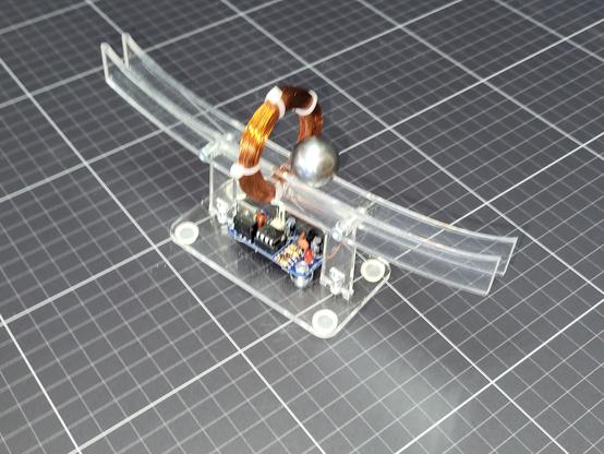Maxwell's Cradle II is A desktop toy that shows the power of magnetism. A steel ball runs on a slightly curved acrylic track, being given a small "kick" by the electromagnetic coil in the center.
