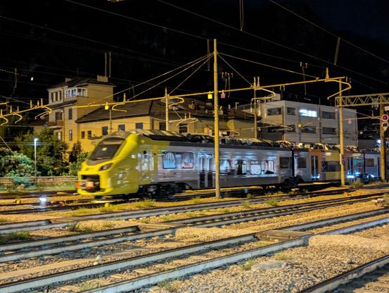 Alstom Coradia Stream ETR160 EMU in grey-green livery, blurry as it is moving through an illuminated station in darkness