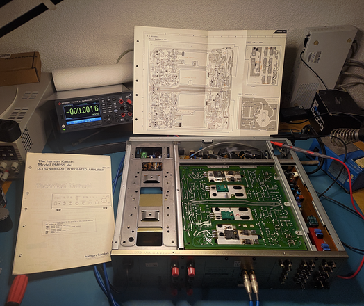 A HK PM655 Vxi amp, opened up and upside down, on an electronics workbench. The service manual with the annotated PCB is in the background. Also visible is a Keysight 34461A DMM and assorted other tools.