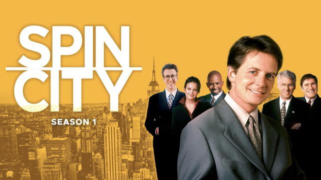 Promo shot of Spin City, season 1. The Words "Spin City" in white lettering dominate the left half of the frame with a monchrome skyline of NYC beneath it. Cast members dominate the right half with Michael J Fox in foreground, others behind. Background is yellow.