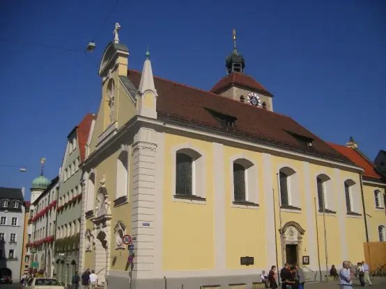 The image appears to depict a historical building with a distinctive architectural style. It features a yellow facade, large windows, and a clock on the roof. The structure likely has cultural or historical significance, as suggested by its design. There are people walking in front of the building, and the sky is clear and blue. If you have specific questions about this place or need information, feel free to ask!

Image Credits: Wikimedia / Szeder László / CC BY-SA 4.0