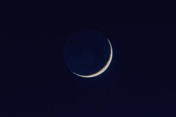 Waxing crescent moon on a dark blue sky.