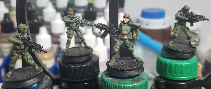 4 near future looking sci-fi troopers with automatic rifles. The female figure is painfully cheesecake with low riding pants and a bare midriff
