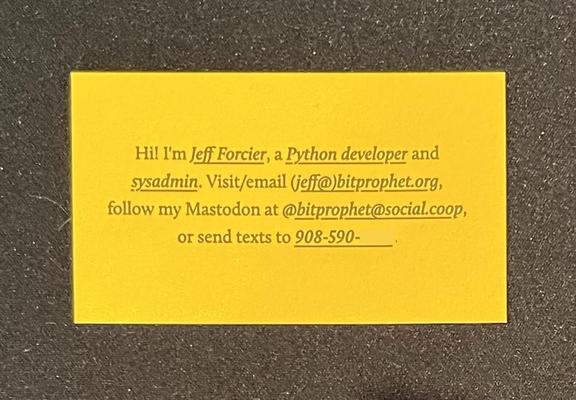 Photo of a completely removed business card, top down, showing the vibrant (but quite nice in person, maybe a little saturated in the photo) yellow cardstock, black letterpressed text in a serif font. It reads:

“Hi! I’m Jeff Forcier, a Python developer and sysadmin. Visit/email (jeff@)bitprophet.org, follow my Mastodon at @bitprophet.social.coop, or send texts to 908-590-XXXX.”

and the identifiers (name, roles, email etc) are all underlined. The text is all tastefully centered on the card and split up across 4 lines.