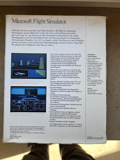 The image features the back cover of the Microsoft Flight Simulator software package, primarily in German. It outlines features of the simulator, including the ability to develop piloting skills, learn aircraft maneuvers, and experience different flight conditions. The cover includes a