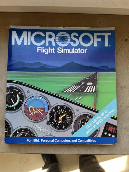 Cover of a Microsoft Flight Simulator software box featuring an illustration of an airplane cockpit with various dials, and a runway with mountains in the background. The text indicates compatibility with IBM personal computers and mentions color display capabilities on RGB monitors.