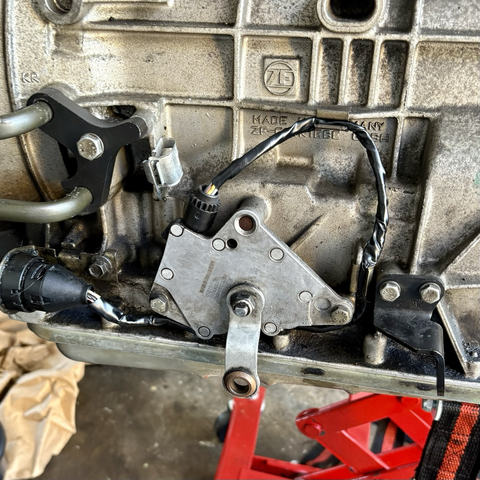 A set of wires leading to a wiring harness along the side of the ZF transmission bound for my 2003 BMW 5-series station wagon, more or less neatly wrapped with black electrical tape.