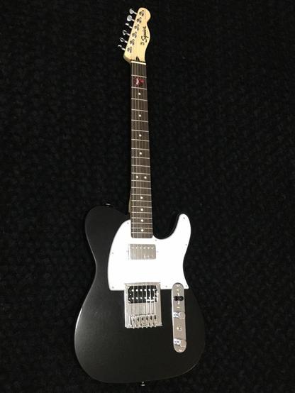 Picture of my black Squier Telecaster, upgraded with full size CTS pots, an Oak Grigsby switch, Switchcraft output jack, Orange Drop cap, coil split toggle switch, Wilkinson tuners, bridge and humbucker pickups. It has a white pick guard and an Indian Laurel fretboard.
