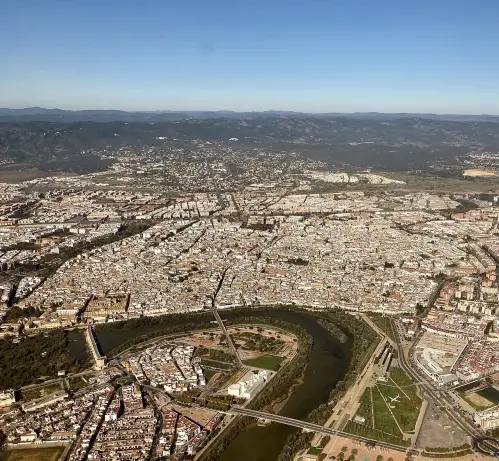 The image appears to show an aerial view of a city, featuring dense urban areas, buildings, and a winding river that runs through it. There are mountains or hills in the background, suggesting a varied landscape. The image likely captures a scene with clear skies and is set in a region that might be associated with rich architecture and history. Would you like more details or context about the location?

Image Credits: Wikimedia / kallerna / CC BY-SA 4.0