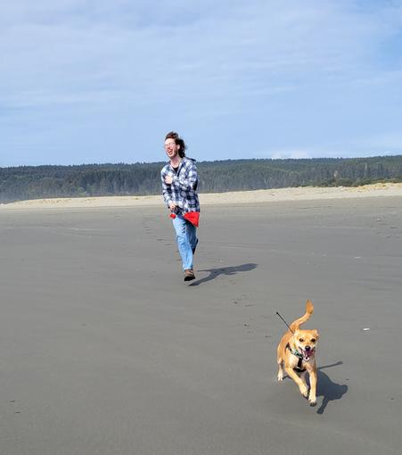 Laughing boy and his cinnamon colored dog racing toward the waves