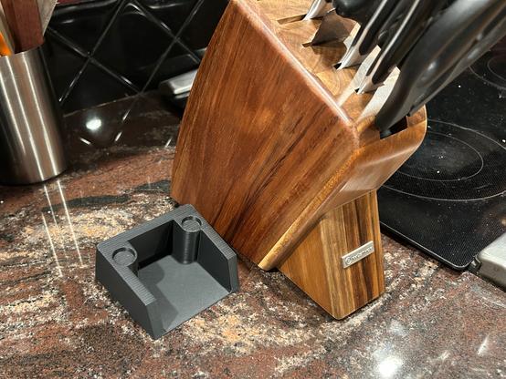 A 3D printed hollow wedge shape is beside the knife block.