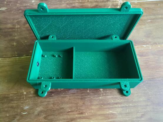 Green 3D-printed case and matching lid. There are tabs on the box and lid to bolt them together. There are also tabs on the bottom of the box to screw it to a wall or chimney.
