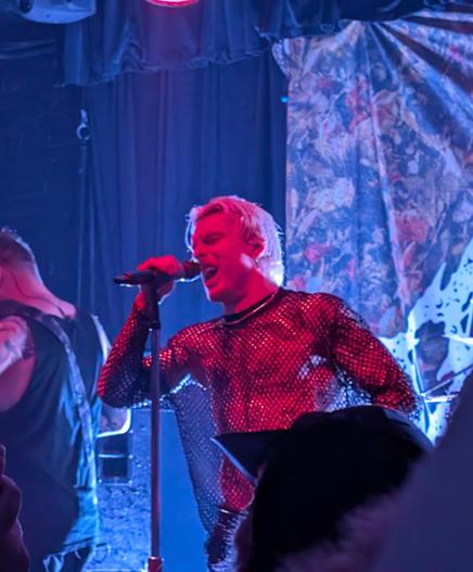 The lead signer of Paleface Swiss holding the microphone on its stand by his right hand, screaming with passion.