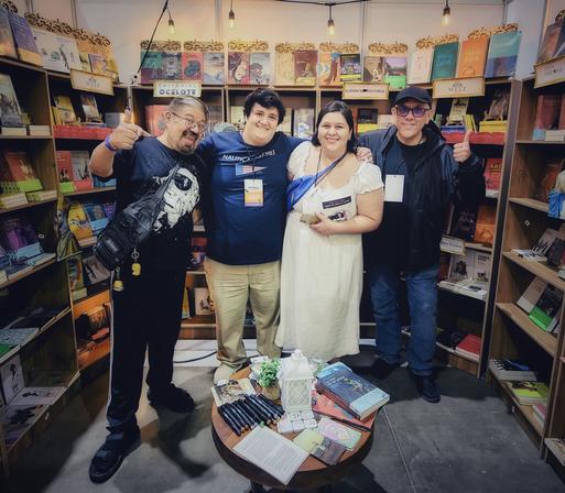 Cuatro personas posan en el stand de la librería 1567 Books en la Feria Nacional del Libro de León, Guanajuato.