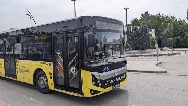 A yellow city bus on a huge road crossing.