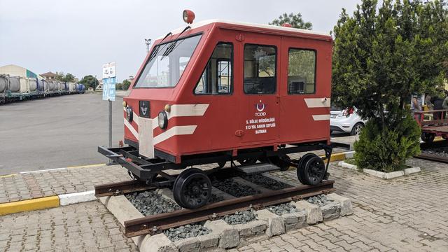 A tiny, red TCDD maintenance track car displayed in front of the station.