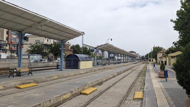 A small railway station. The tracks are paved and there's no dedicated crossing across the tracks.