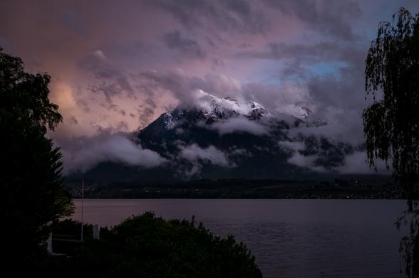 Berg und See mit interessantem Licht- und Wolkenspiel in der Abenddämmerung.