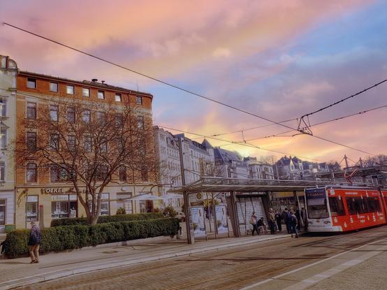 Straßenbahnhaltestelle in Plauen, im Hintergrund Häuser, der Abendhimmel blau, gelb , rot.