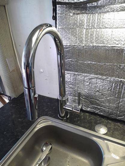 Just a vege-washer type tap fitted to a black bench top next to a stainless steel sink.