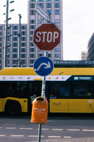 hochformatiges foto, im hintergrund ein hochhaus, ein gelber bus der linie 200, im vordergrund ein straßenschild (Alte Potsdamer Straße), darunter verkehrsschilder und ein orangener Mülleimer mit der aufschrift "Müll"