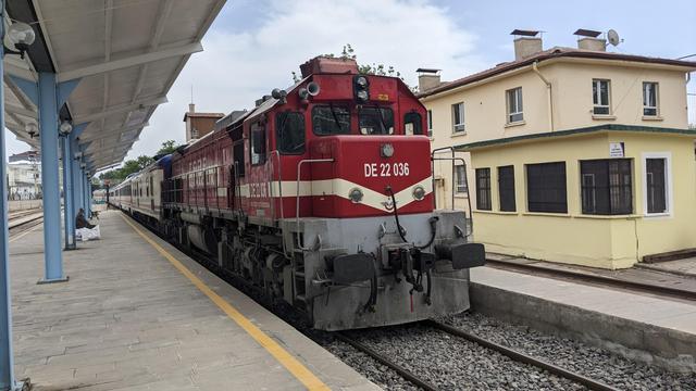 A red TCDD class DE 22000 locomotive hauling my train.