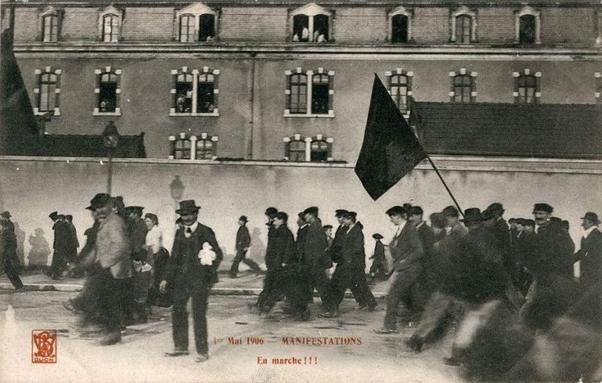 Photo de manifestants avec un drapeau noir, avec le sous-titre "en marche !!!"