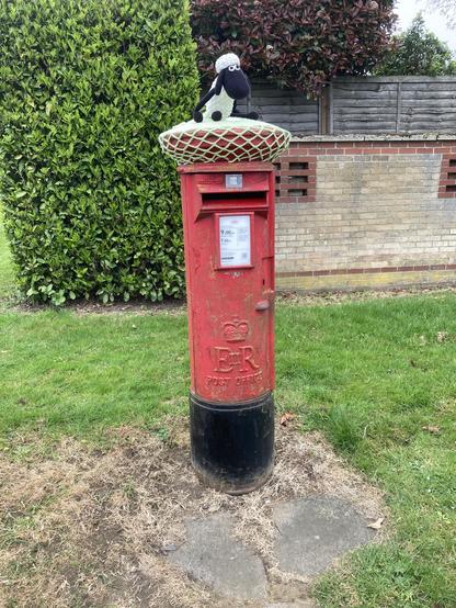 Red British post box with crocheted ‘topper’ featuring Shaun the Sheep