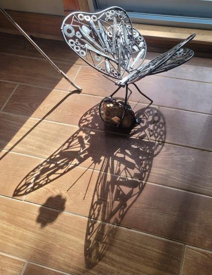 Sur la photo le même papillon mais pas peint et déposé par terre au soleil de sorte qu'on voit la belle ombre du papillon.