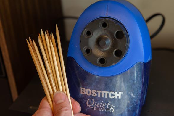 A bunch of bamboo skewers being held to show off their sharpness next to my trusty Bostitch Quiet Sharp 6.